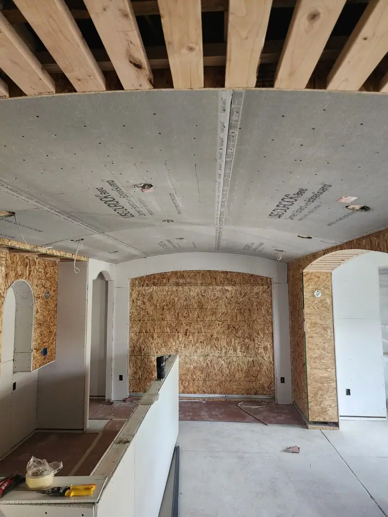 Drywall ceiling and arched openings being hung over OSB walls