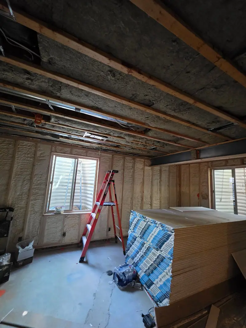 Basement with spray-foam insulated walls and open joists before drywall