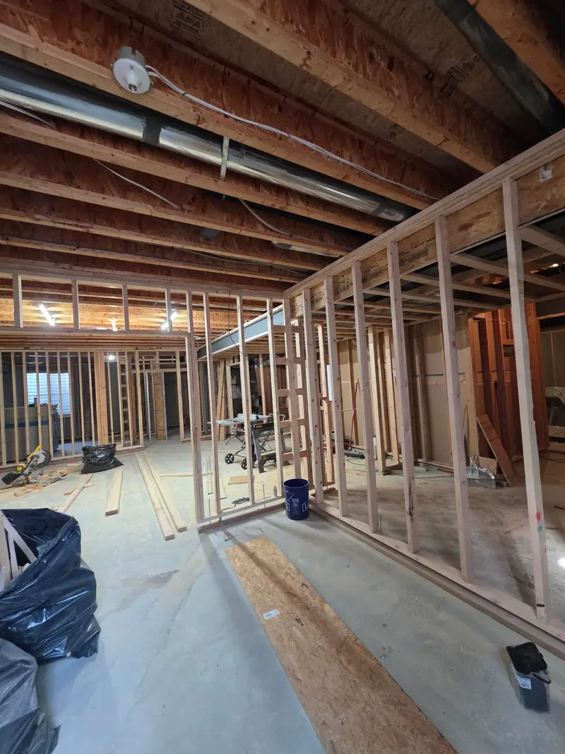 Long run of new basement stud walls with lumber and tools on the concrete