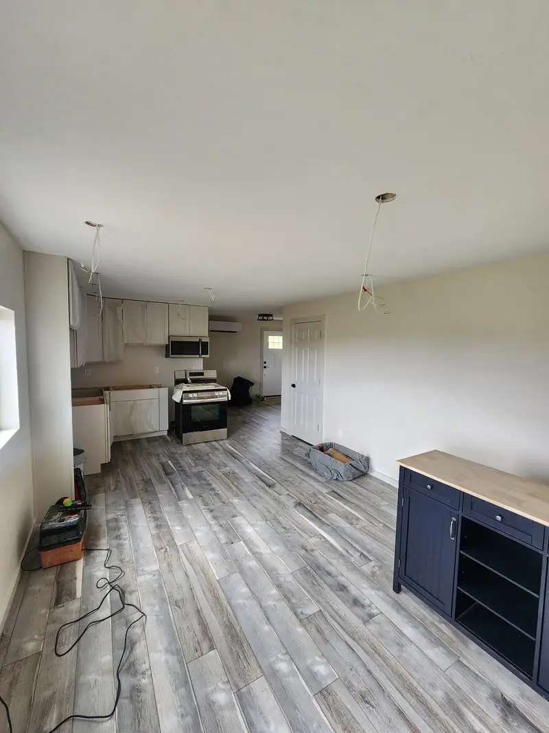 Finished basement apartment kitchen with white cabinets, stainless range and grey plank floors