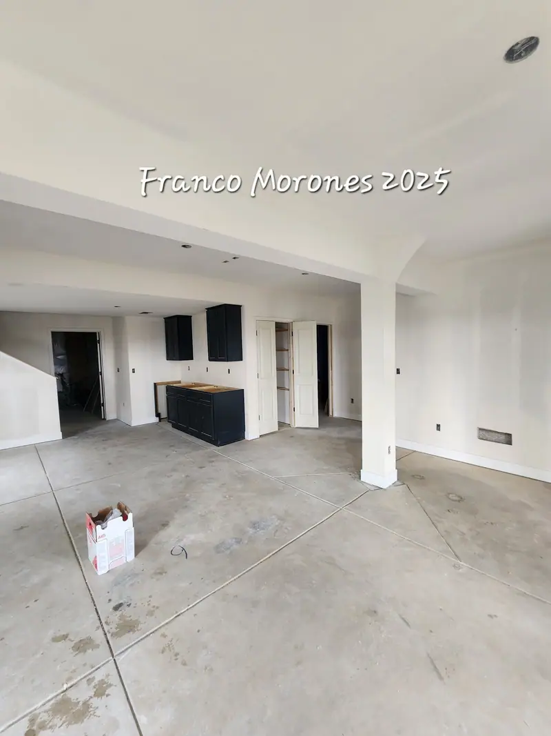 Basement finish in progress with drywall up, black cabinets and concrete floor