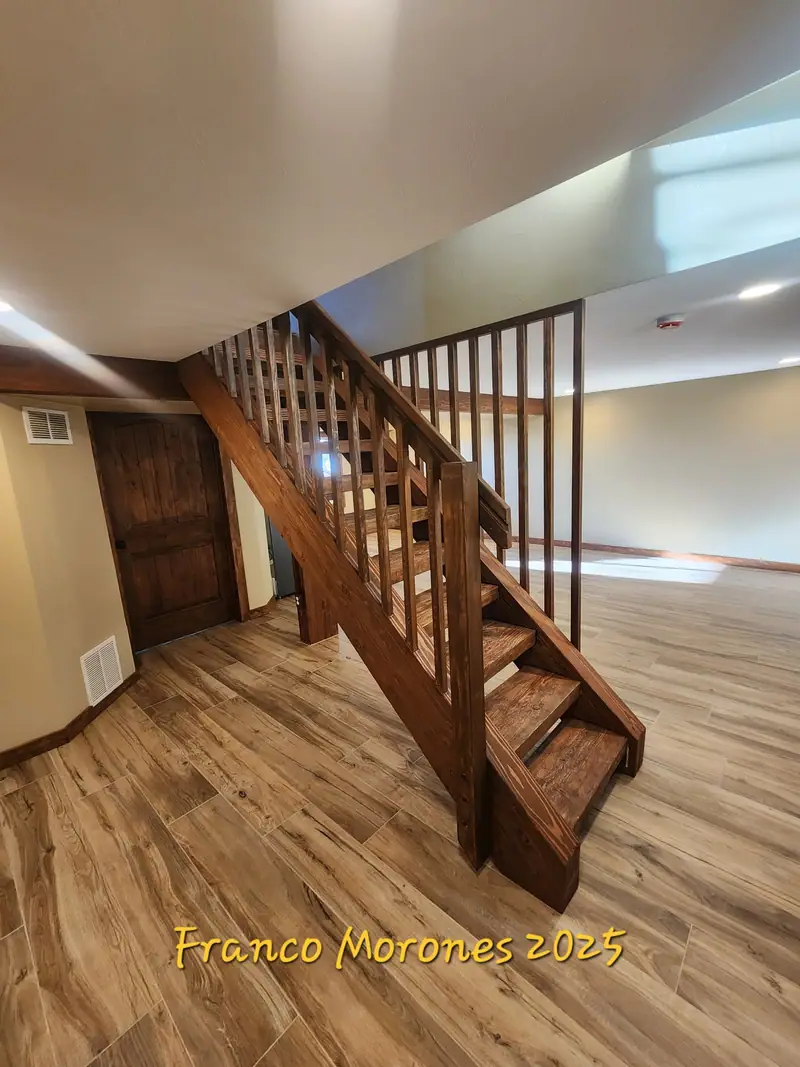 Finished basement with a custom stained wood staircase, square balusters and wood-look plank floor