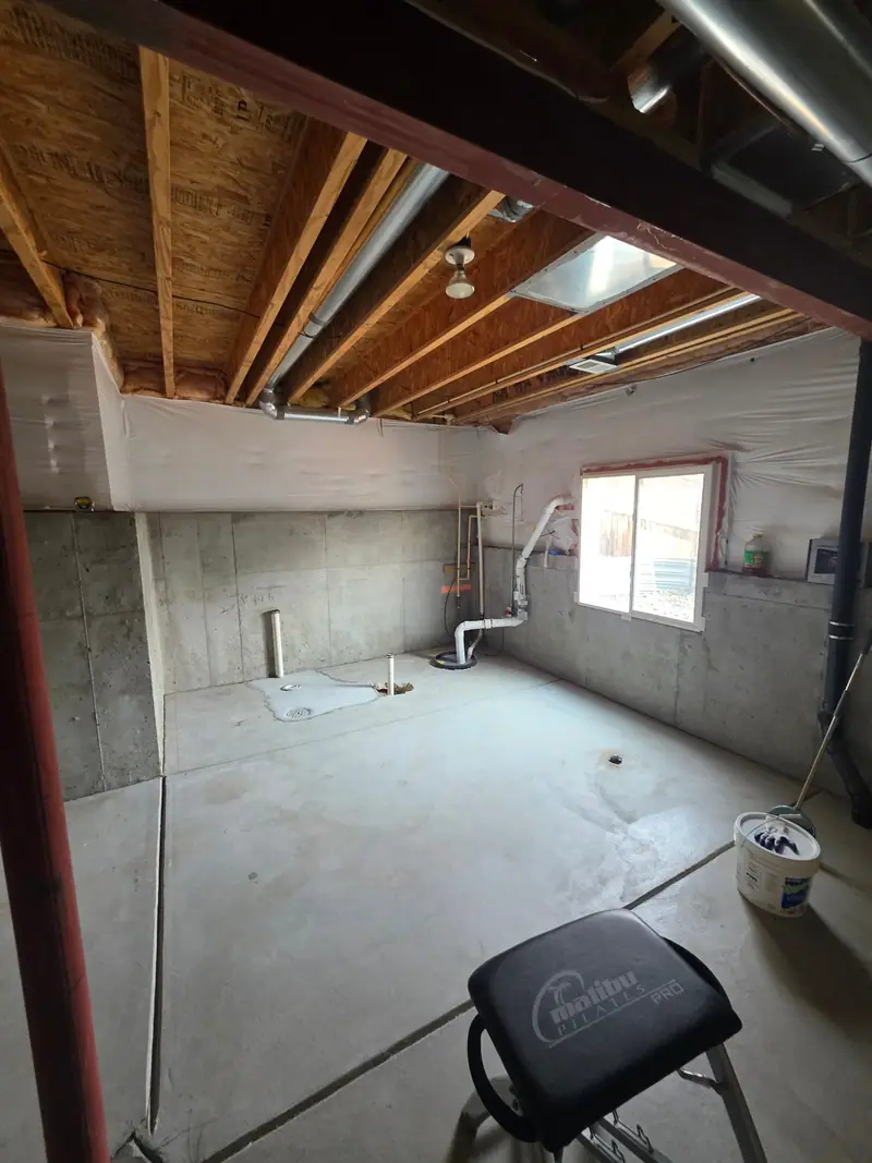 Unfinished basement with a window, concrete walls and exposed ductwork before finishing