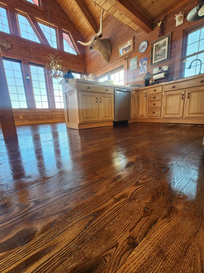 Log home kitchen with honey oak cabinets and glossy hardwood floors