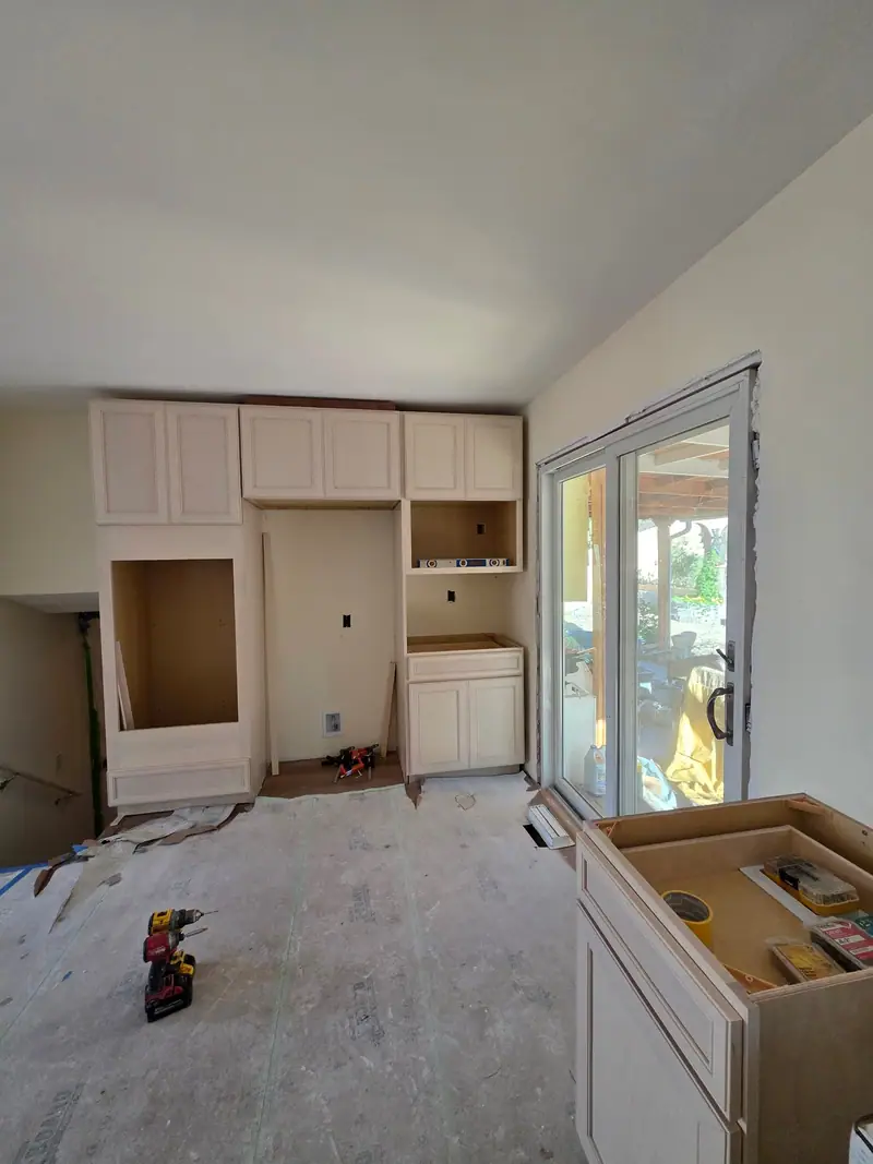 White cabinets being installed in a kitchen remodel before the counters go on
