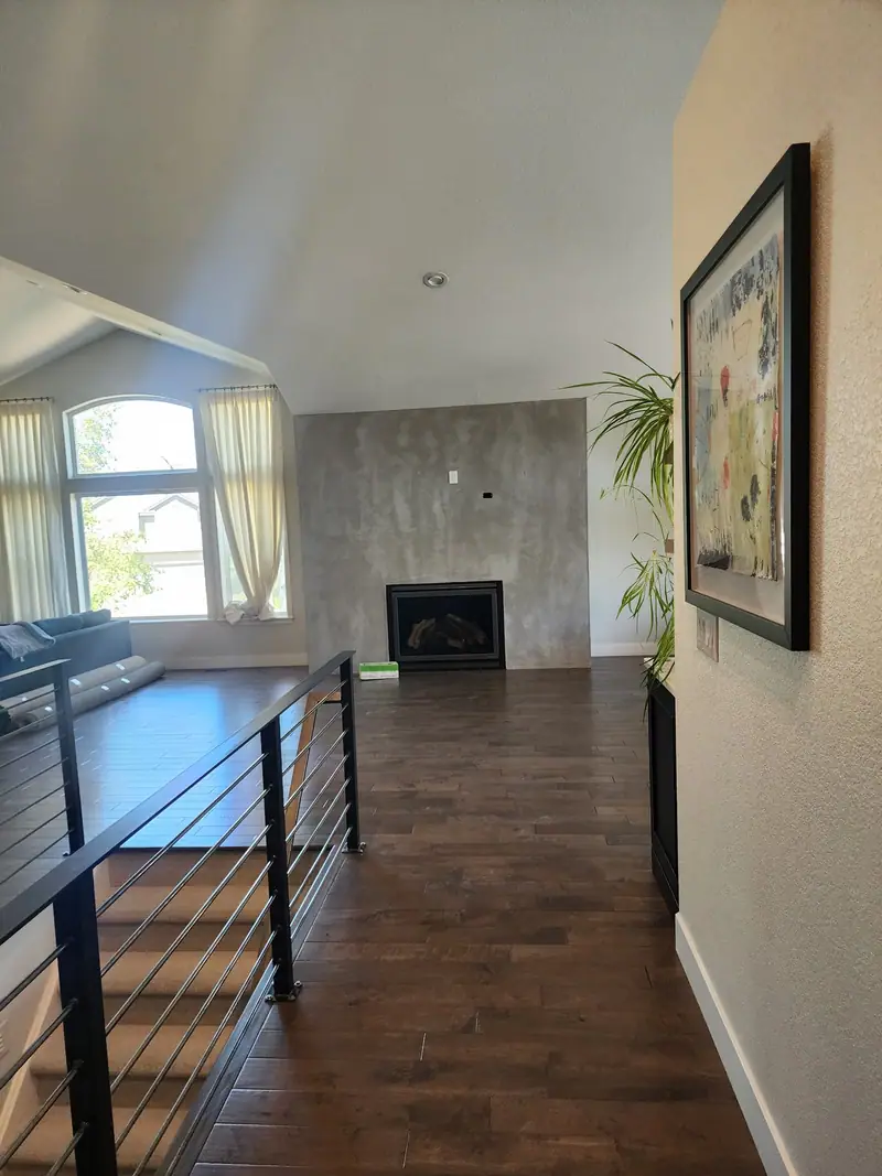 Living room with cable railing, dark wood floors and a fireplace wall