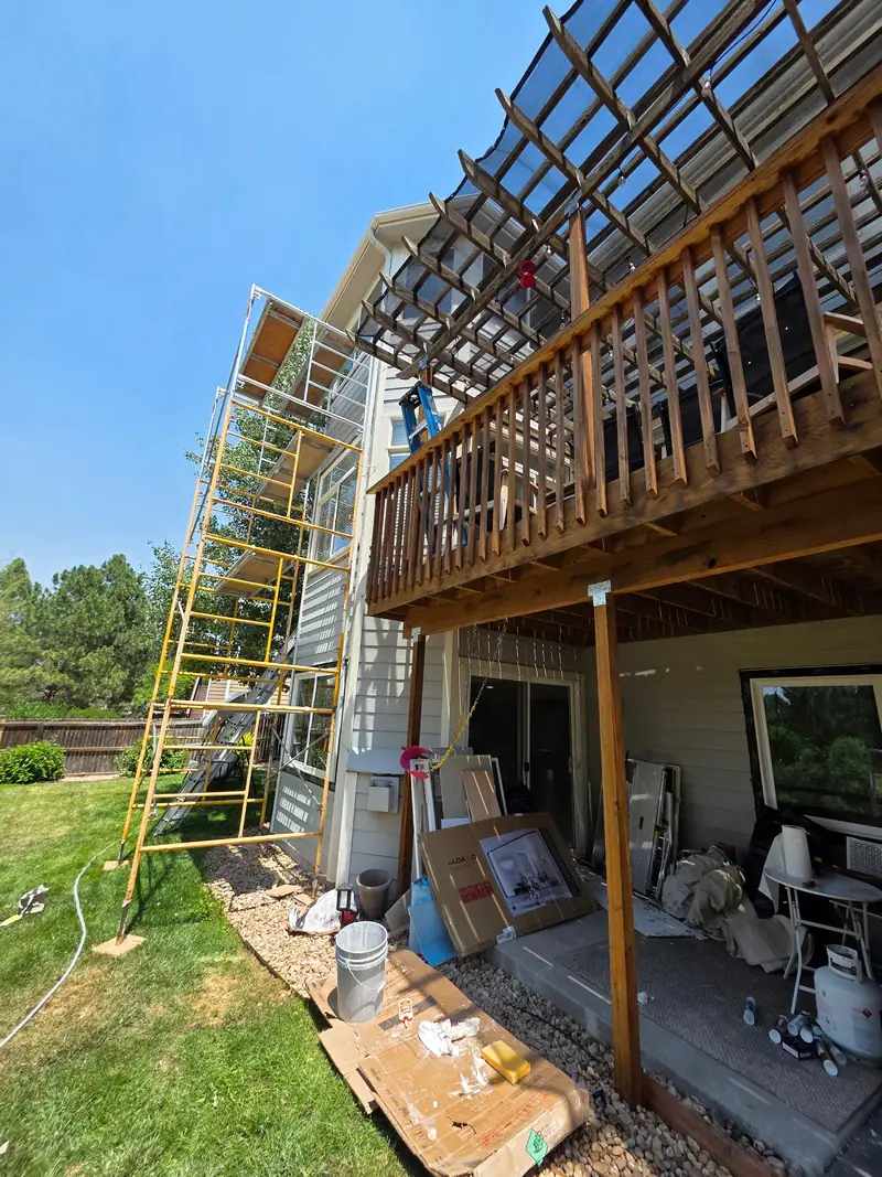 Wood deck and pergola under construction with scaffolding against the house