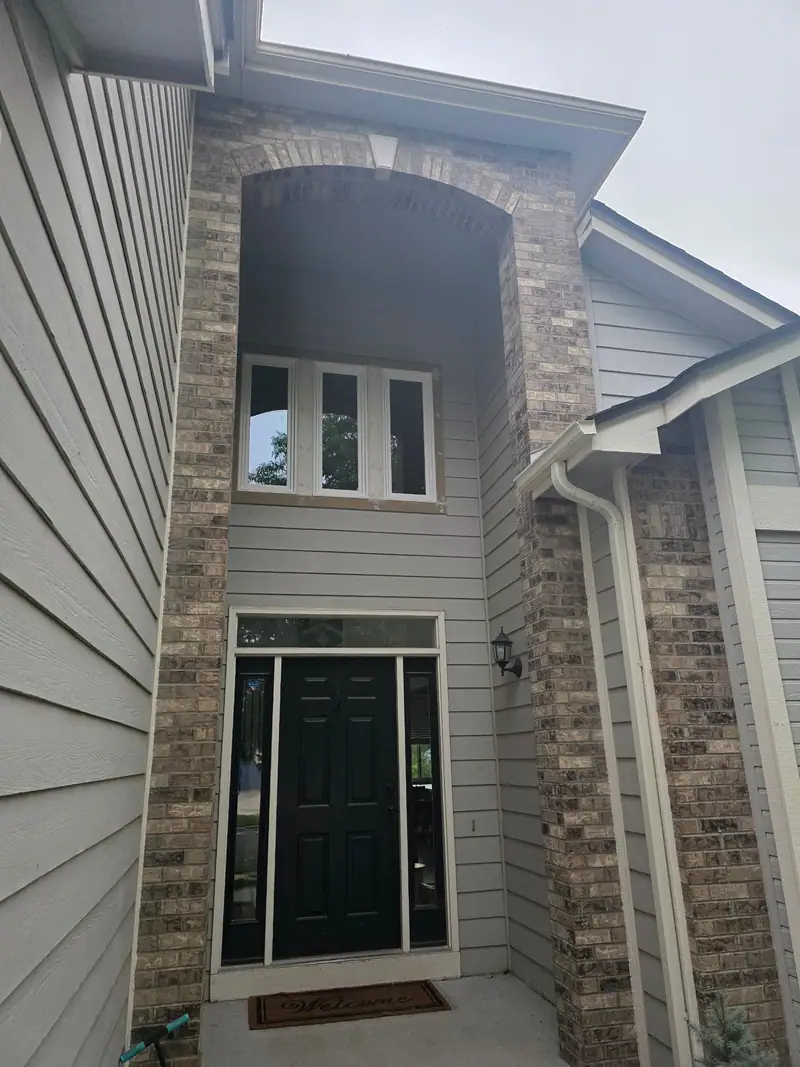 Brick-framed front entry with a dark green door and tall sidelights