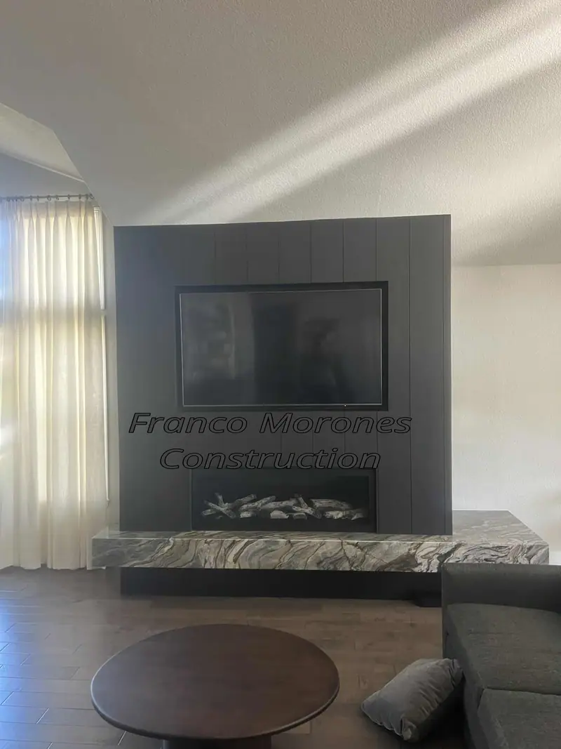 Finished fireplace feature wall with dark vertical panels, linear fireplace, TV recess and thick stone hearth ledge