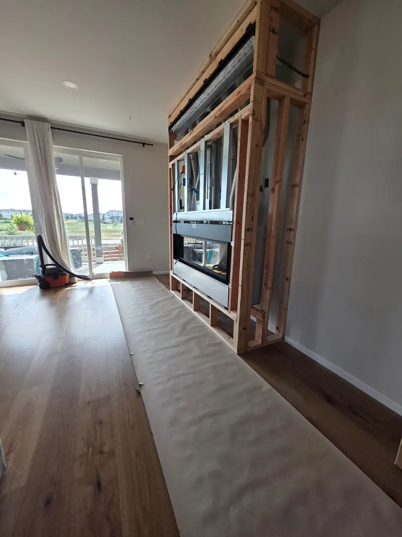 Fireplace feature wall framed in lumber around a linear firebox in a living room