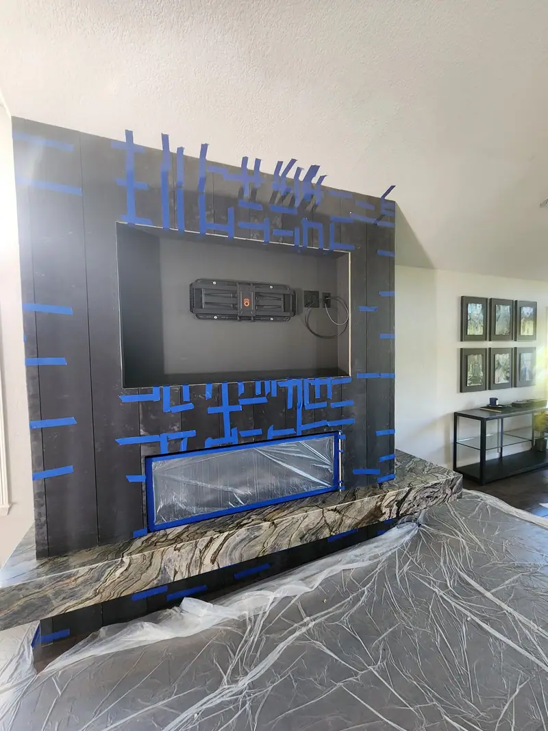 Fireplace feature wall mid-build with dark panels, blue tape and the stone hearth ledge set