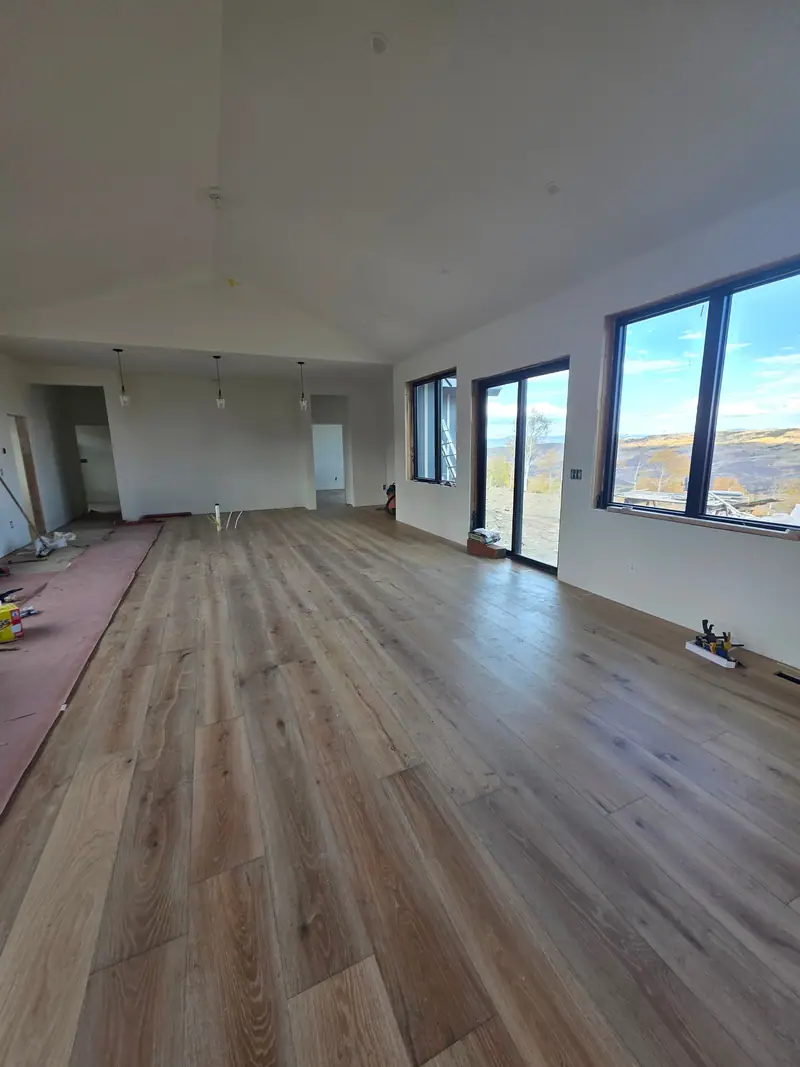 Long open room with new wide plank floors and big windows