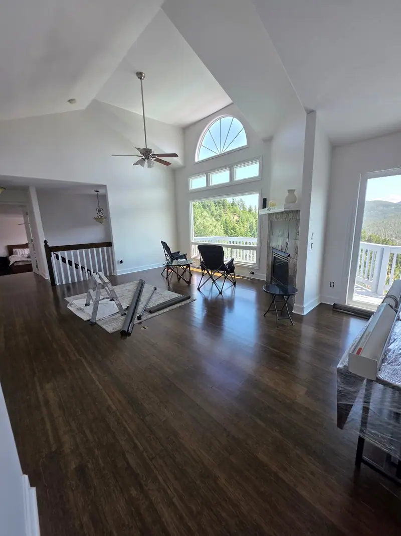 Great room with new dark hardwood floors, white stair railing and an arched window