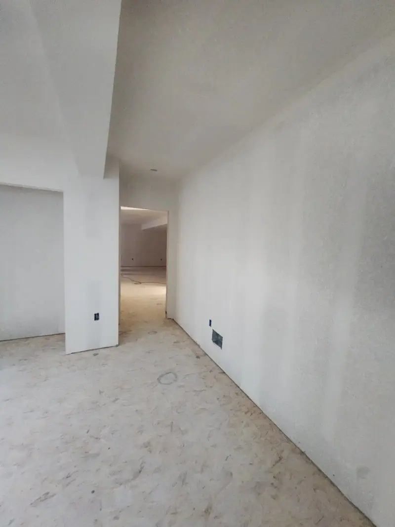 Long hallway freshly hung and finished in drywall