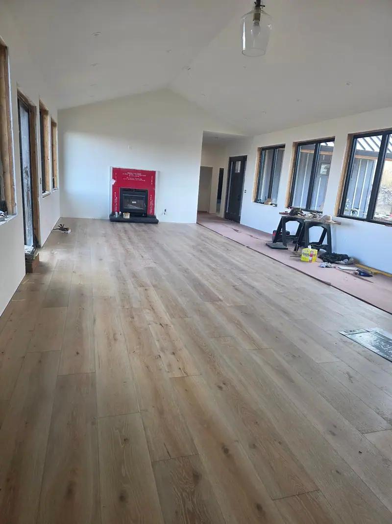 Long room with new plank flooring and a red fireplace at the far end