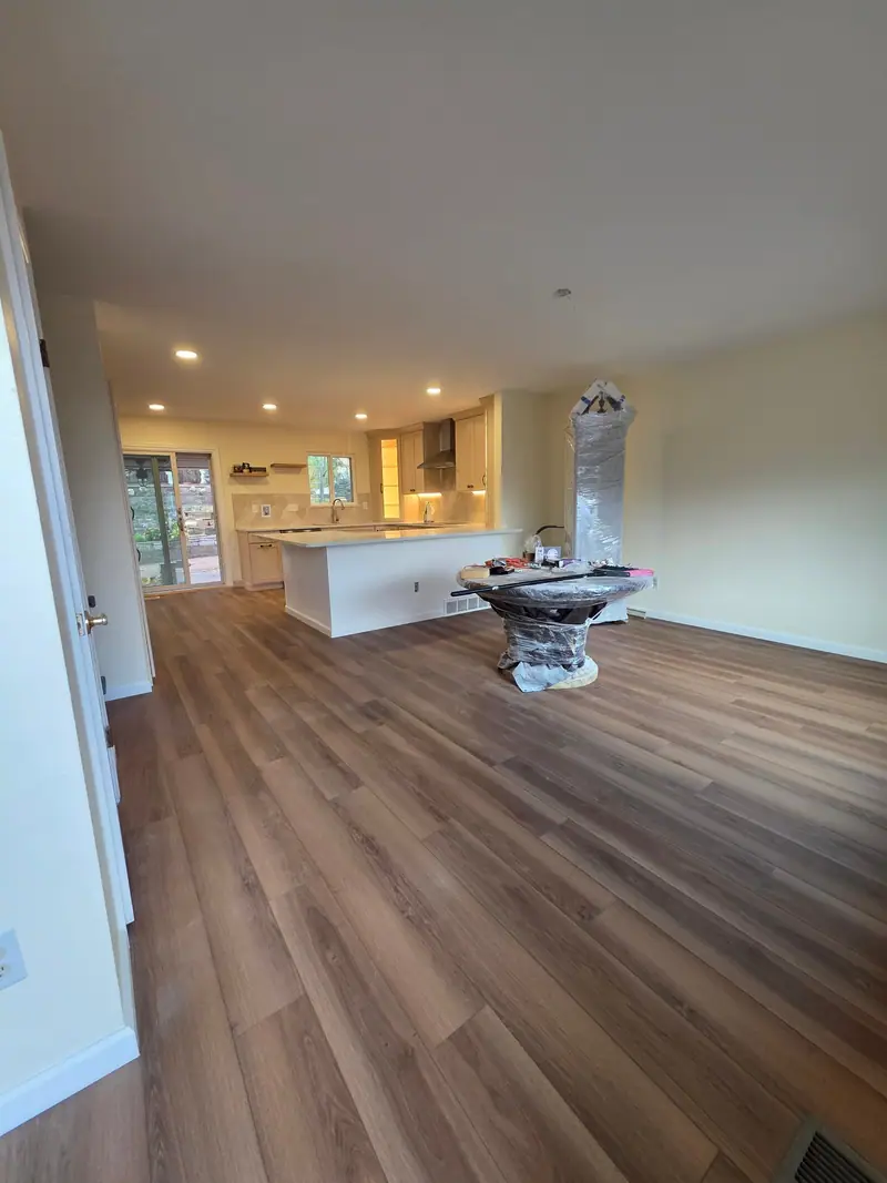 Open kitchen and living area with new wood-look plank floors during a remodel