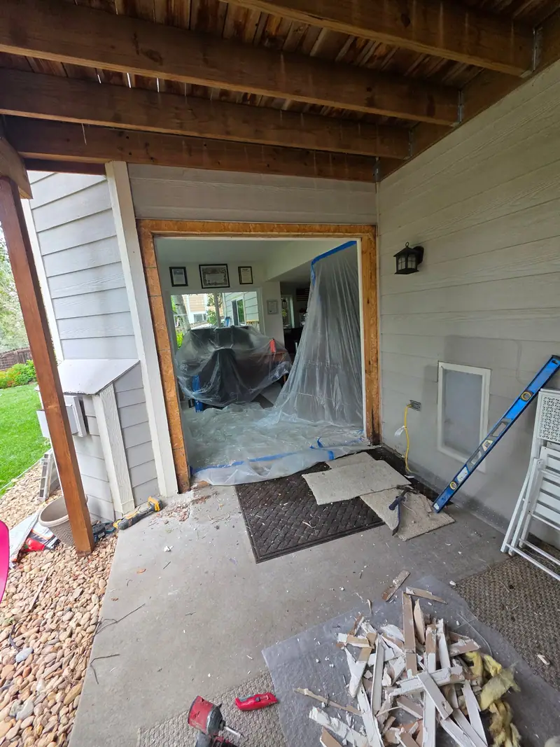 Exterior wall opened up under a deck for a new door with plastic sheeting inside